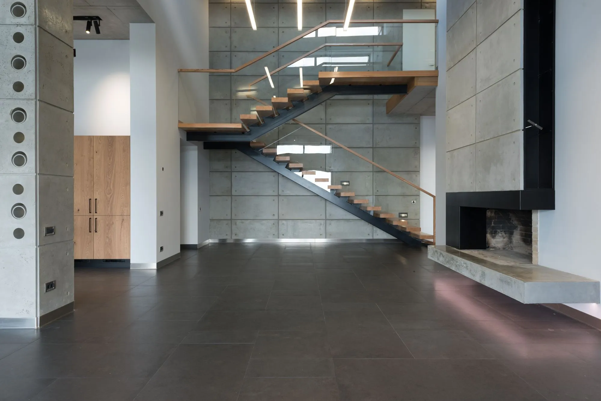 Escalera de madera junto a un muro de concreto visto; imagen de referencia.